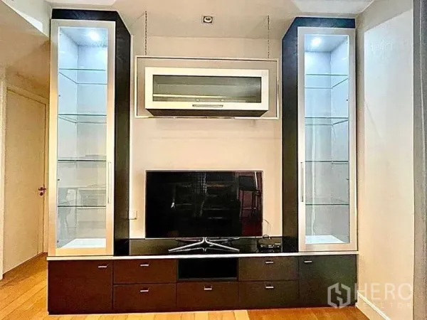 Condominium for rent in Bangkok - Built-in TV wall with glass display cabinets and storage drawers.