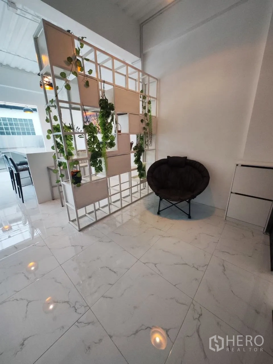 Home Office for rent in Bang Na, Bangkok - Bright ground floor with marble-look tiles and a decorative plant partition.