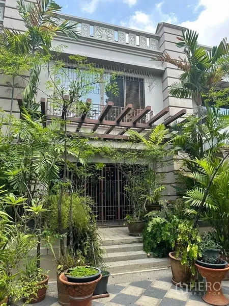 联排别墅 出租在Khlong Toei, Bangkok - 曼谷空堤区联排别墅外立面，热带花园、木格棚与铁门入口。