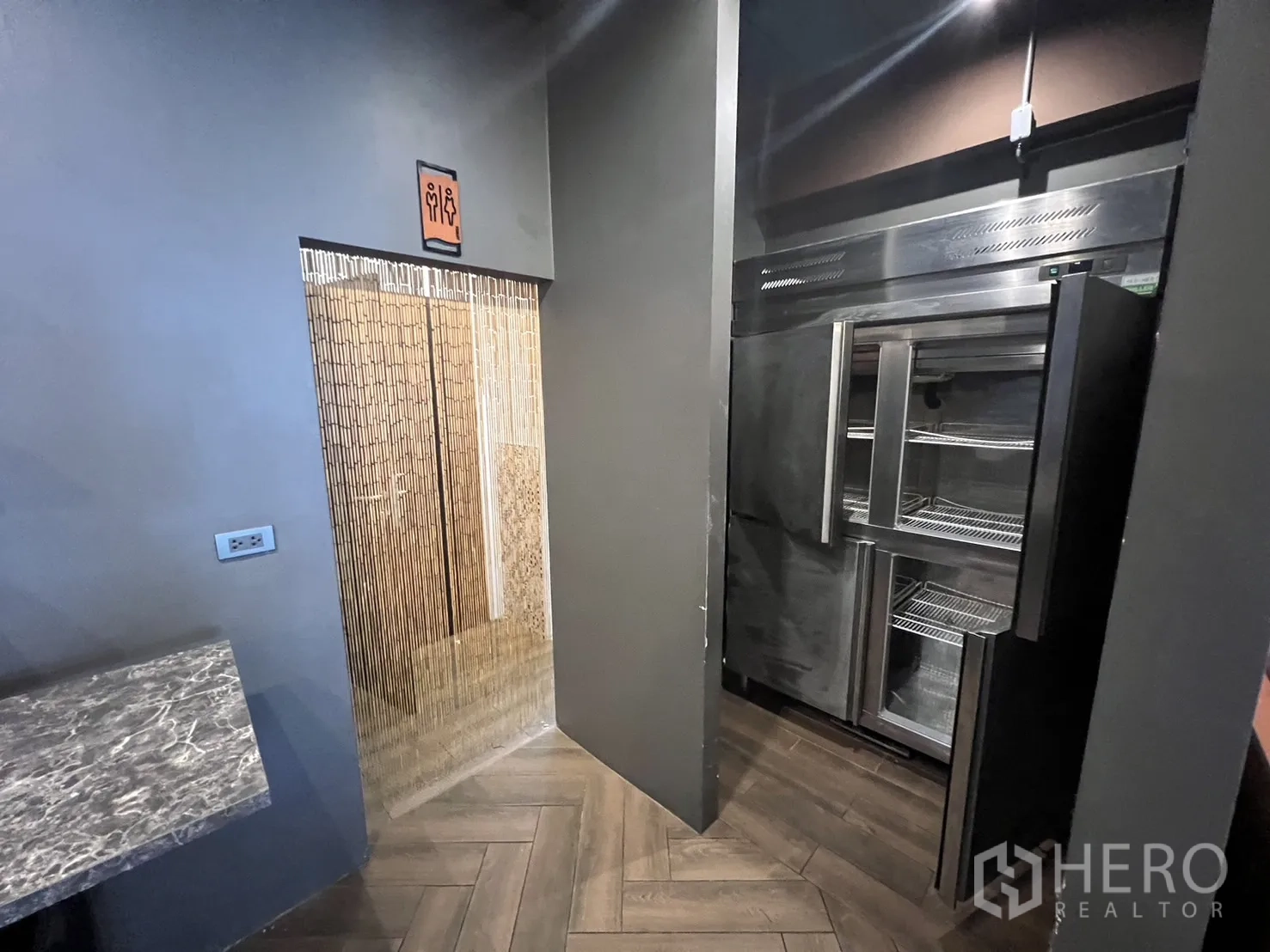 Retail Space for rent in Watthana, Bangkok - Entrance to restrooms with bamboo-style doors adjacent to a stainless refrigeration unit.
