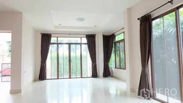Detached House for sale in Bang Phli, Samut Prakan - Bright living room with large sliding glass doors, corner windows and dark curtains.
