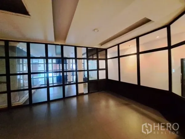 Shophouse for rent in Watthana, Bangkok - Room with dark tiles and black-framed glass partitions for office use.