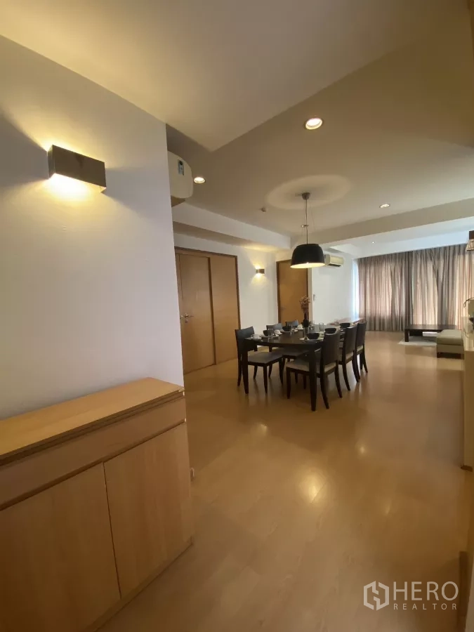 Condominium for rent in Watthana, Bangkok - Hallway view to the dining room with wall sconces and built-in cabinet leading to a bright living area.