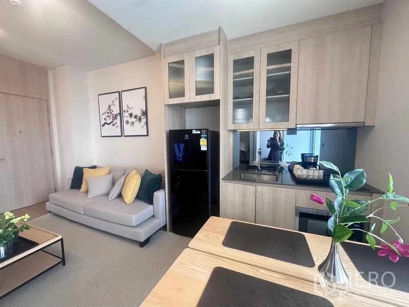 Condominium for rent - Open-plan kitchen with wood cabinetry, black countertop, fridge and adjacent sofa.