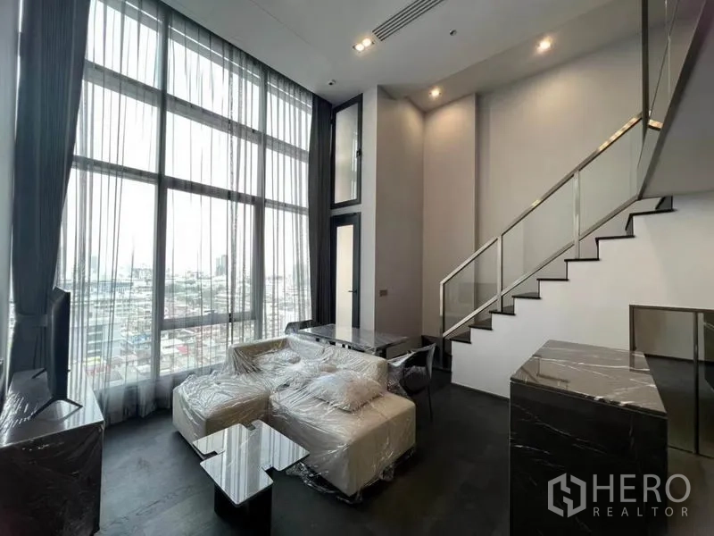 คอนโด ให้เช่าในRatchathewi, Bangkok - ห้องนั่งเล่นสไตล์ลอฟต์ เพดานสูง หน้าต่างสูงจรดเพดาน เห็นวิวเมือง ในคอนโดย่านราชเทวี