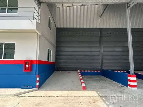 货栈 出租在Samut Prakan - 近景：遮雨装卸区，卷帘门、导向护栏和消防箱
