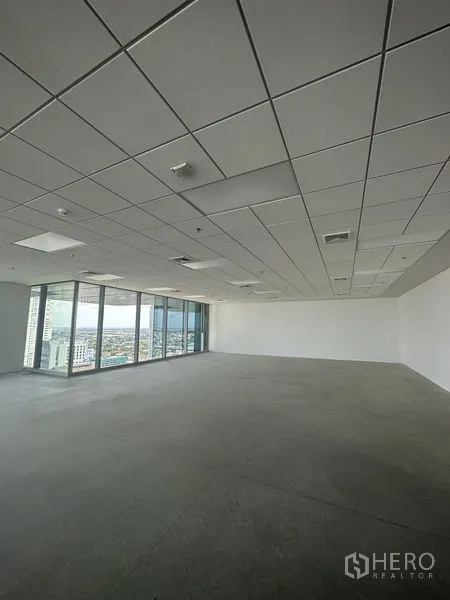 Office Space for rent in Bang Na, Bangkok - Unfurnished office corner with glass curtain wall, city views and recessed ceiling fixtures.