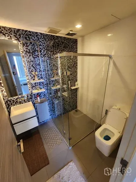 Condominium for rent or sale in Bang Rak, Bangkok - Bathroom featuring a frameless glass shower, rain shower, and mosaic tiles.