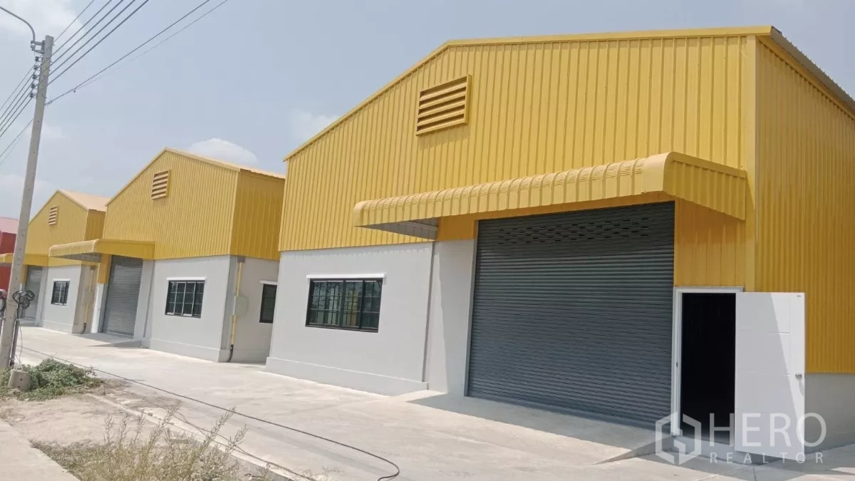 คลังสินค้า ให้เช่าในNonthaburi - โกดังหลังคาเหลืองเรียงกัน ประตูม้วนขนาดใหญ่ พร้อมถนนคอนกรีตหน้าอาคารในปากเกร็ด นนทบุรี