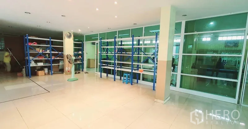 Office Space for rent in Bang Kho Laem, Bangkok - Spacious storage or operations zone with blue metal racks and a full-height glass wall.