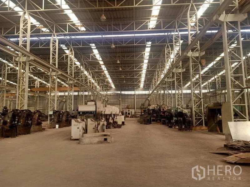 Warehouse for rent in Mueang Samut Sakhon, Samut Sakhon - Long central aisle under skylights flanked by heavy-duty press machines.