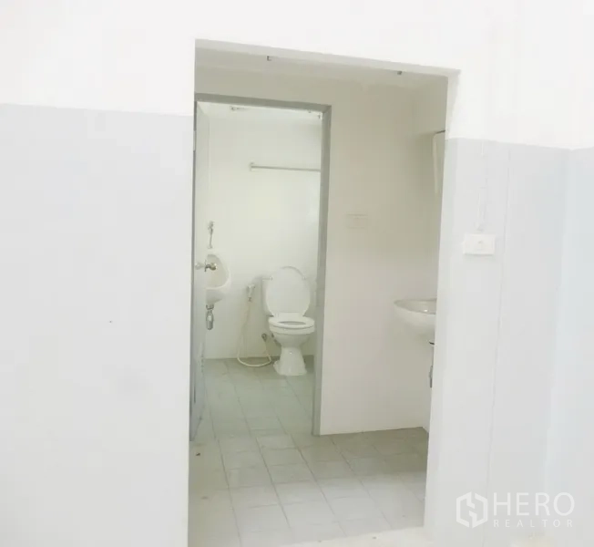 Factory for rent or sale in Pathum Thani - Clean restroom inside the facility with toilet, urinal and washbasin on tiled flooring.