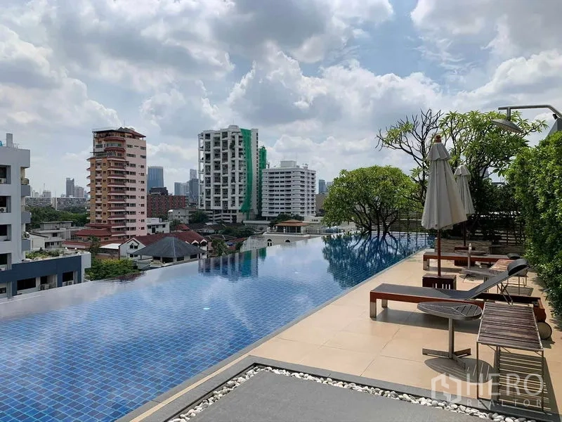 Condominium for rent or sale in Khlong Toei, Bangkok - Rooftop infinity pool with sun loungers and Bangkok city skyline views.