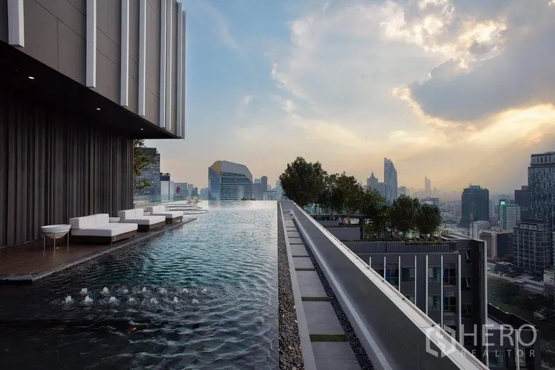 คอนโด ให้เช่าในPathum Wan, Bangkok - สระว่ายน้ำอินฟินิตี้บนดาดฟ้าพร้อมเตียงอาบแดดและวิวเมืองยามเย็น