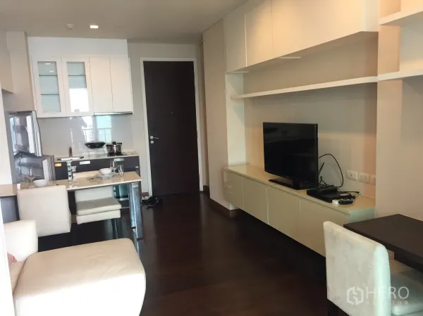 公寓 出租在Watthana, Bangkok - 通罗公寓的开放式客厅，带电视柜、壁柜、用餐吧台与紧凑厨房。