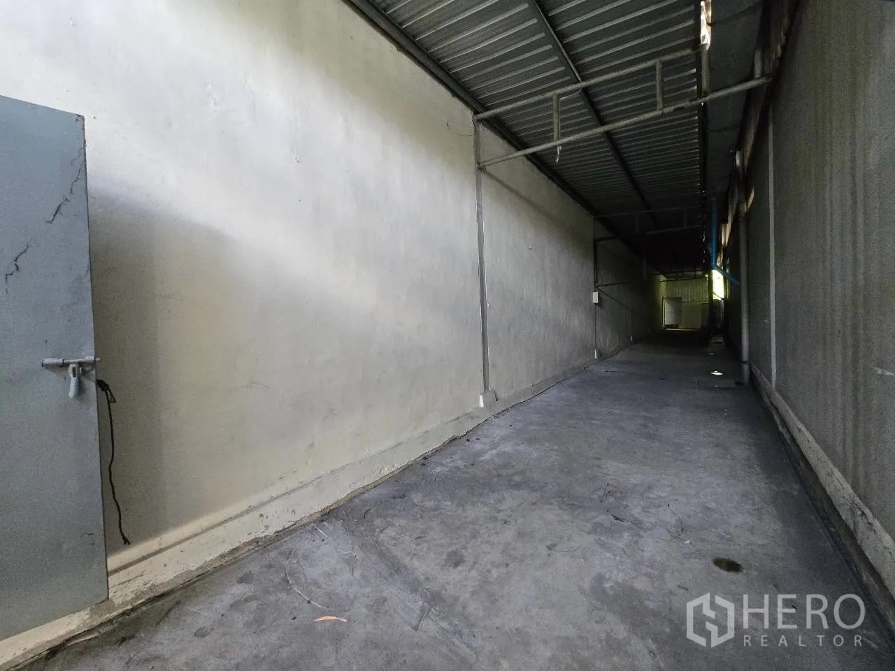 Warehouse for rent or sale in Mueang Samut Sakhon, Samut Sakhon - Covered side corridor with metal roofing and a concrete floor inside the compound.