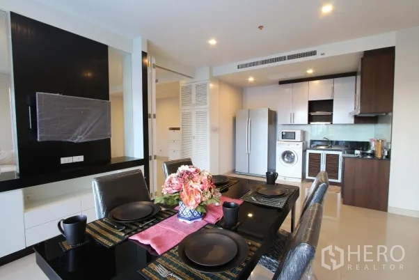Condominium for rent in Watthana, Bangkok - Open‑plan dining area with black table setting overlooking a modern kitchen in a Bangkok condo.