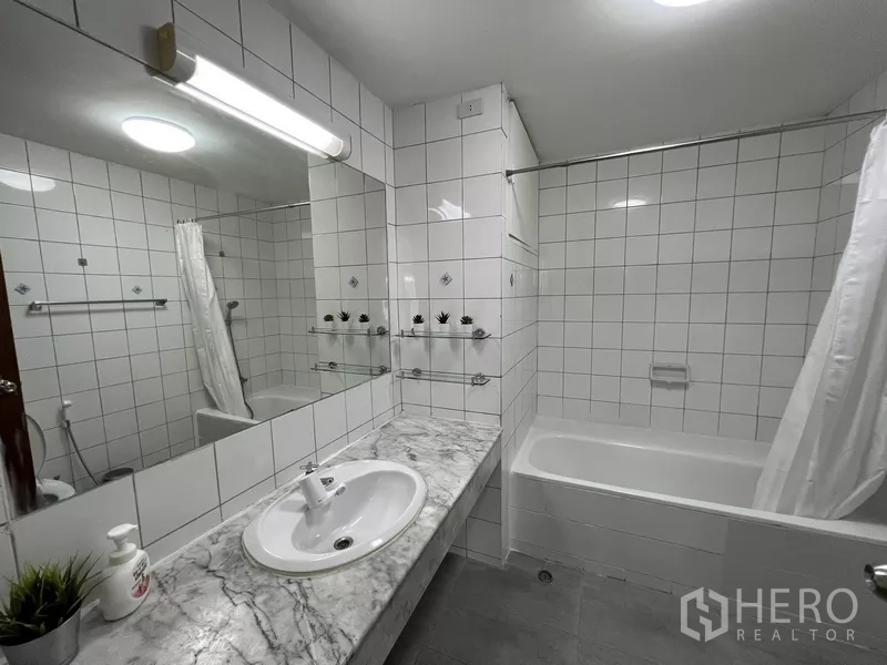 Townhouse for rent or sale in Suan Luang, Bangkok - Bathroom with white tiles, marble counter and bathtub with shower curtain.