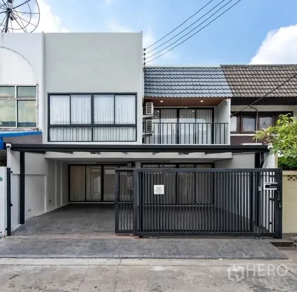 联排别墅 for rent in Watthana, Bangkok - 现代两层联排别墅外观，带金属滑动大门、有顶车位、大窗与二层阳台