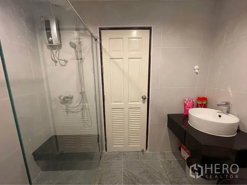 公寓 出租或出售在Watthana, Bangkok - 现代化浴室，玻璃淋浴间、花洒与台上盆，灰色瓷砖。