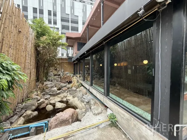 Detached House for rent in Watthana, Bangkok - Side garden with bamboo fence, rock stream and pond beside large glass windows.