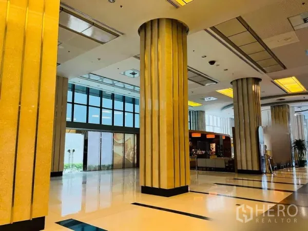 零售空间 出租在Khlong Toei, Bangkok - 高挑零售中庭，立柱与亮面地坪，天花灯带旁有咖啡柜台