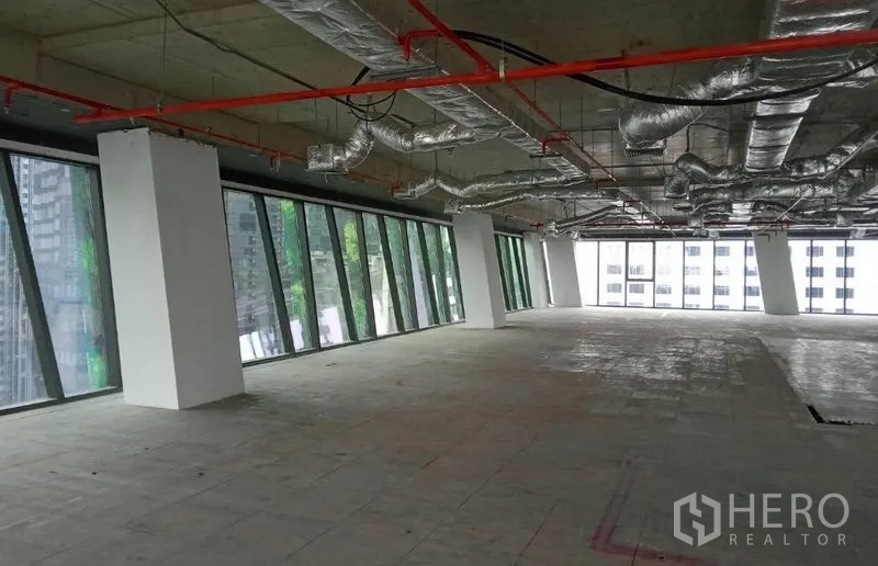 办公空间 出租 - 开放式角部办公区，长排倾斜落地玻璃与未完成的水泥地面