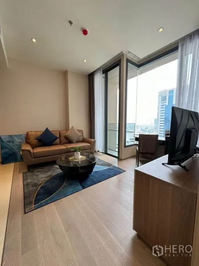 公寓 出租在Watthana, Bangkok - 客厅配沙发与圆形茶几，落地玻璃直达阳台。