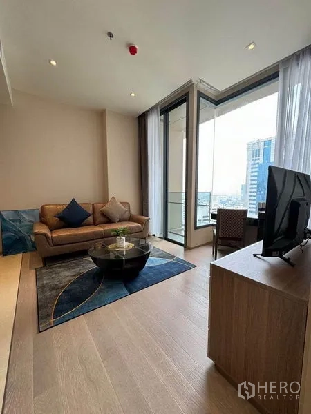 公寓 出租在Watthana, Bangkok - 客厅配沙发与圆形茶几，落地玻璃直达阳台。