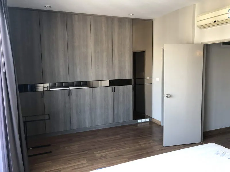 Townhouse for rent in Yan Nawa, Bangkok - Spacious bedroom featuring wall-to-wall built-in wardrobes in grey wood.