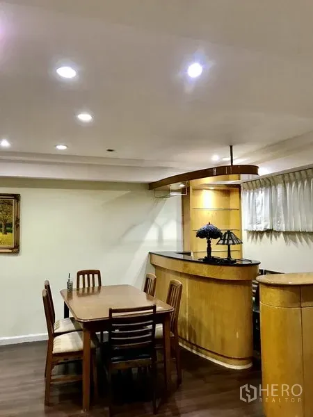 公寓 出租在Watthana, Bangkok - 餐区设木质餐桌椅，紧邻吧台与嵌灯天花。