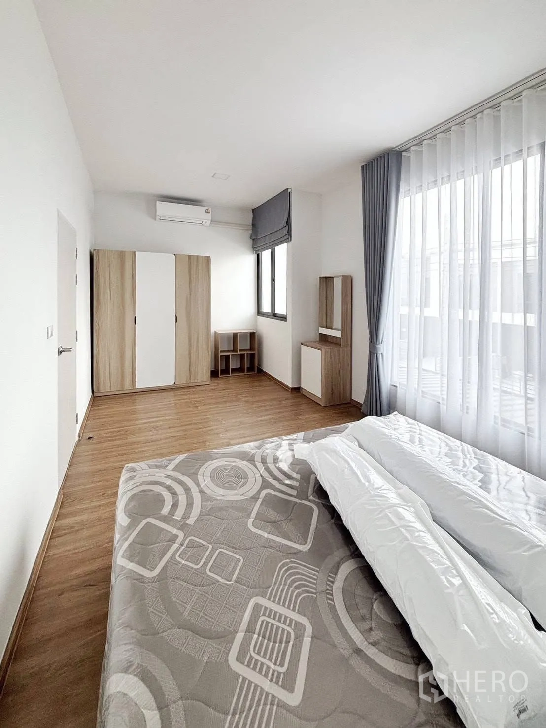 ทาวน์เฮาส์ for rent in Bang Phli, Samut Prakan - ห้องนอนหลักกว้างพร้อมหน้าต่างใหญ่ ผ้าม่านสองชั้น พื้นไม้ ตู้เสื้อผ้า และแอร์
