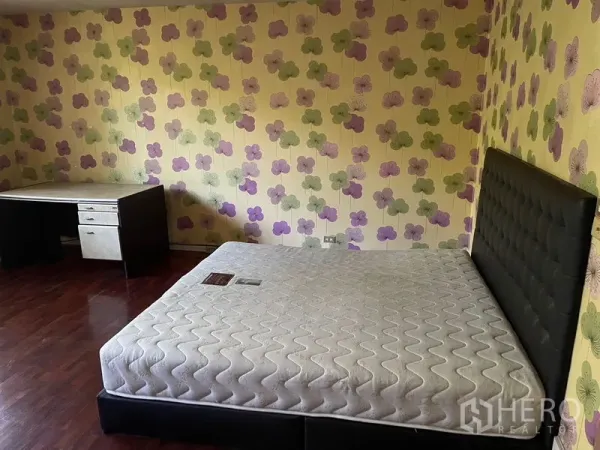Home Office for rent in Watthana, Bangkok - Bedroom with floral wallpaper, wood flooring, upholstered bed and a corner desk.