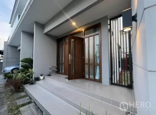 บ้าน ให้เช่า - ทางเข้าบ้านขั้นบันไดกระเบื้อง กระถางต้นไม้ และประตูไม้แข็งแรงยามโพล้เพล้