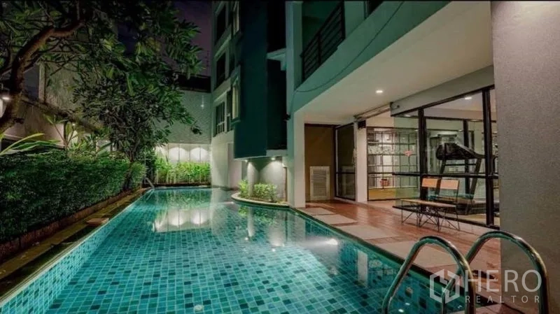 Retail Space for sale in Phra Nakhon, Bangkok - Long tiled pool at night beside a glass-walled gym and manicured hedges.