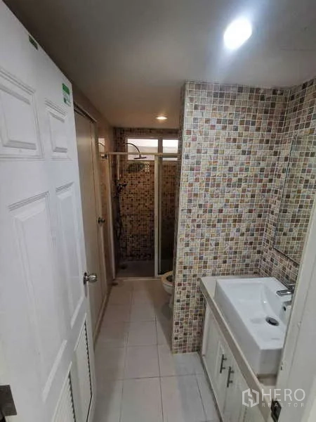 Townhouse for rent in Chatuchak, Bangkok - Bathroom corridor with vanity, sink and shower cubicle at the end.