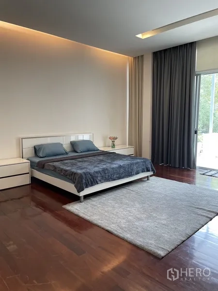 Townhouse for rent or sale in Chatuchak, Bangkok - Spacious master bedroom with large rug, bedside tables and door to the balcony.