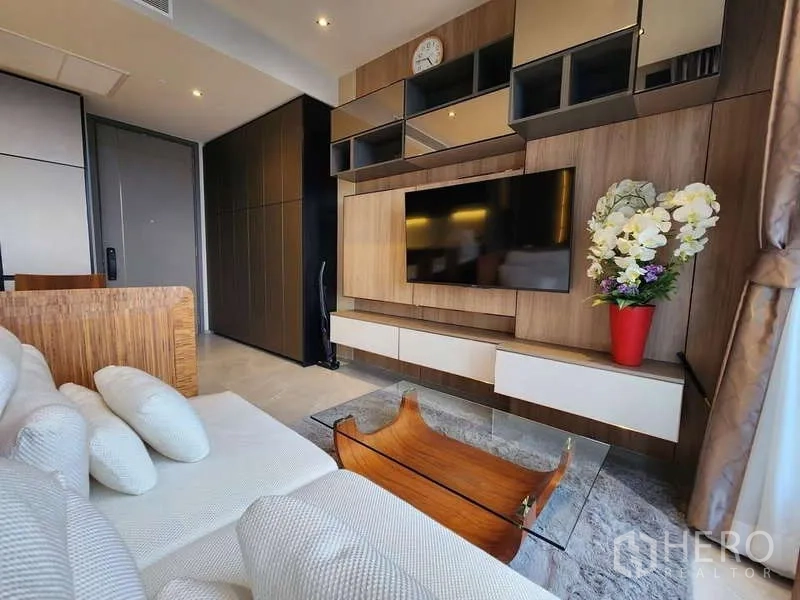 คอนโด ให้เช่าในWatthana, Bangkok - โซฟาอบอุ่นหันหน้าเข้าหาผนังทีวี หน้าต่างสูงจรดเพดานเห็นสกายไลน์