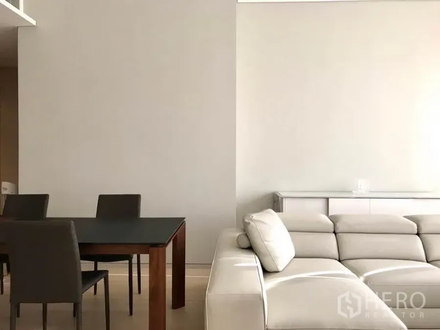 公寓 出租或出售在Watthana, Bangkok - 明亮的客餐厅，米色皮沙发与深色餐桌，极简风格。