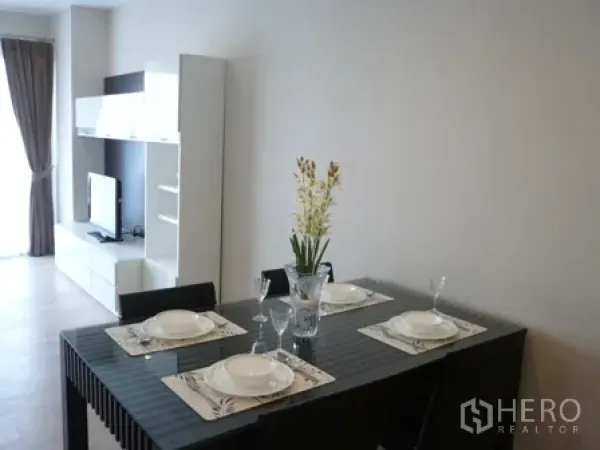 Condominium for rent in Watthana, Bangkok - Glass-top dining table set for four in a light-filled living space.