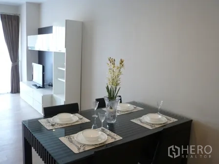 Condominium for rent in Watthana, Bangkok - Glass-top dining table set for four in a light-filled living space.