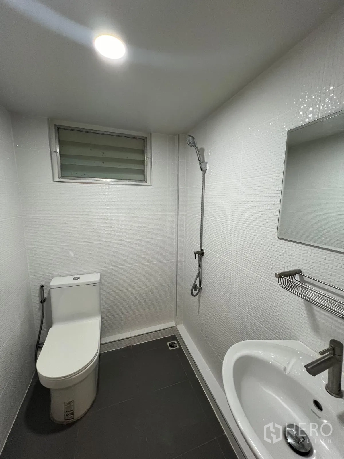 Detached House for rent in Saphan Sung, Bangkok - Compact white-tiled bathroom with shower area, toilet, sink and small window.