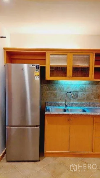 Apartment for rent - Compact kitchen corner with stainless refrigerator, sink and wood cabinets.