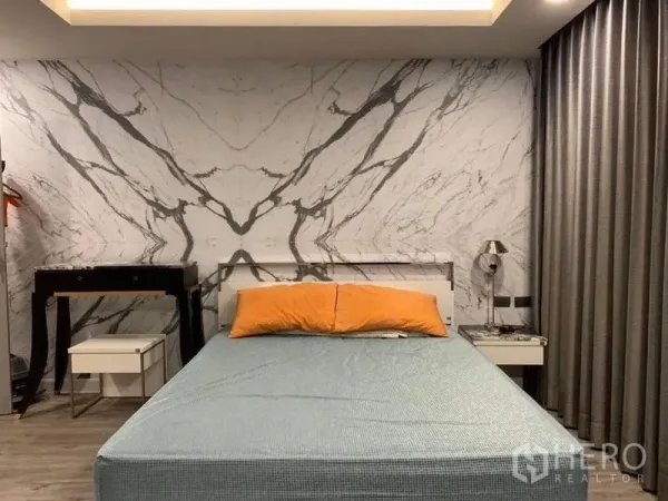 公寓 出售在Khlong Toei, Bangkok - 卧室配大理石纹背景墙、布艺床、橙色枕头及遮光窗帘。