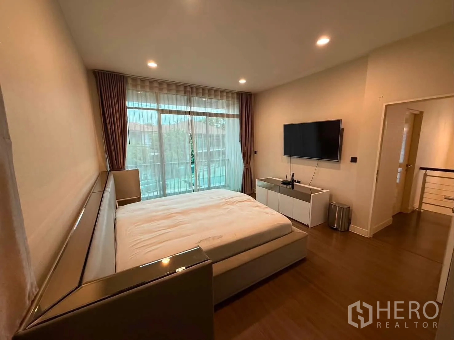 Detached House for rent in Bang Kapi, Bangkok - Bedroom with TV cabinet and wide glass door to a balcony-style window.