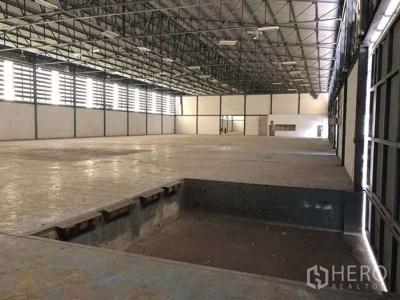 货栈 出租在Khlong Luang, Pathum Thani - 仓库内部带装卸坑位，大面积无柱空间与金属框窗，适合仓储作业。
