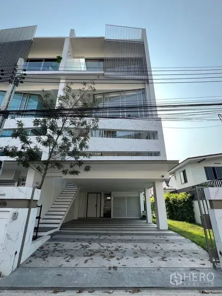 Home Office for rent or sale in Chatuchak, Bangkok - Front facade of minimalist home office with driveway and mature tree.