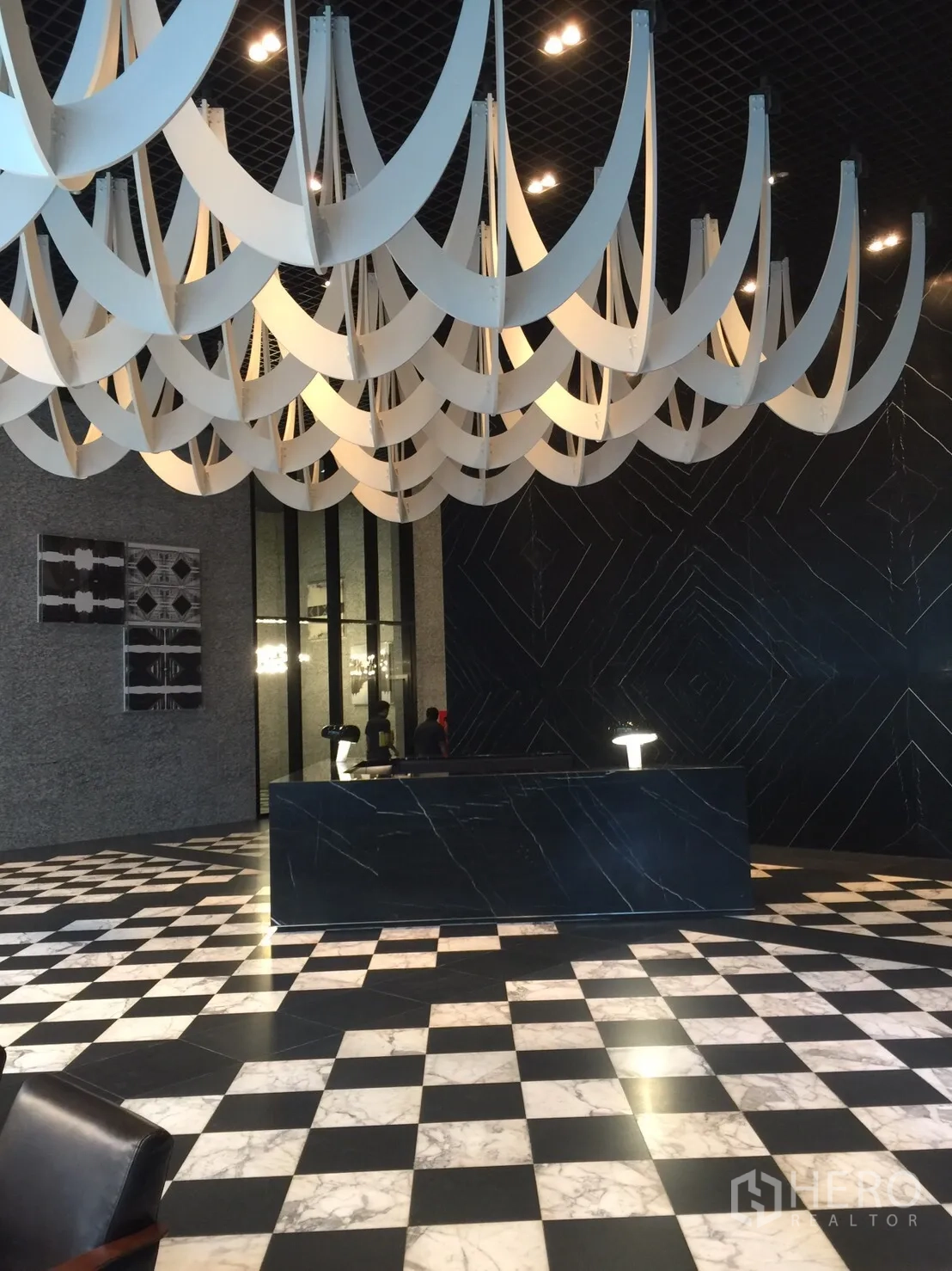 Condominium for sale in Pathum Wan, Bangkok - Grand lobby reception with black marble desk, checkered marble floor, and sculptural ceiling.
