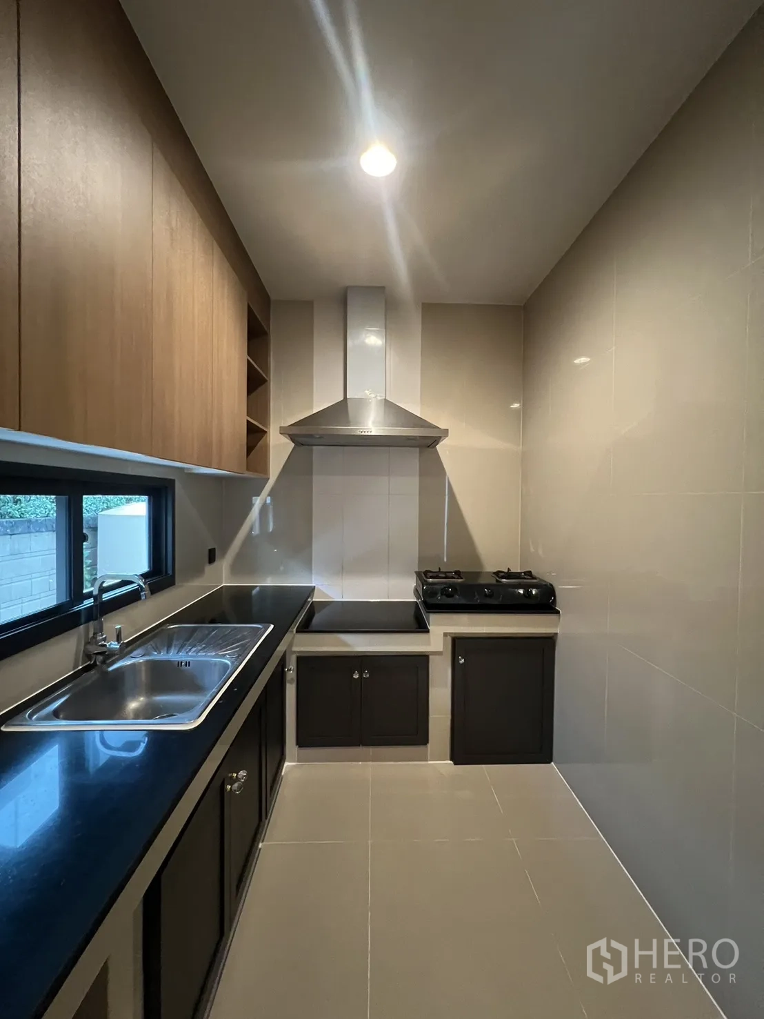 Detached House for rent in Bang Kapi, Bangkok - Closed kitchen with cabinets, sink, gas hob and range hood.