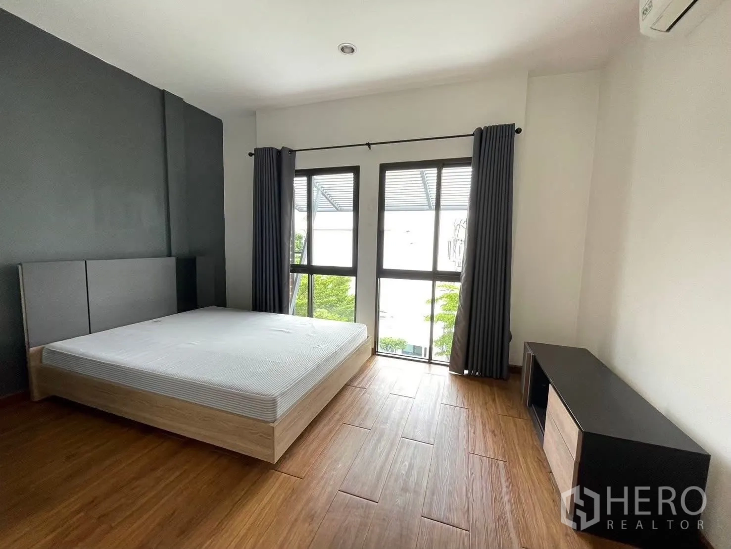Townhouse for rent in Suan Luang, Bangkok - Spacious bedroom with large windows, curtains and a low cabinet.